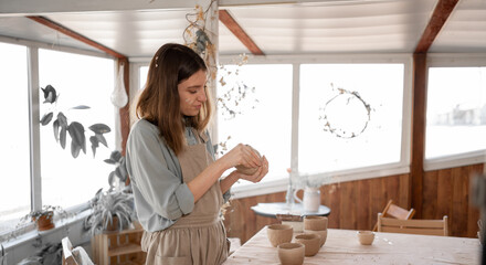 . woman artist sculpts from wet clay in studio. ceramist makes handicrafts from ceramics. female industriousness concept.