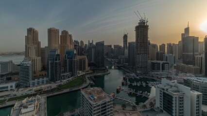 Obraz premium Panorama showing Dubai Marina with several boats and yachts parked in harbor and skyscrapers around canal aerial morning timelapse.