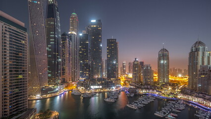 Fototapeta na wymiar Dubai marina tallest skyscrapers and yachts in harbor aerial night to day timelapse.