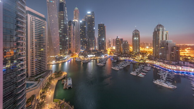 Dubai marina tallest skyscrapers and yachts in harbor aerial night to day timelapse.