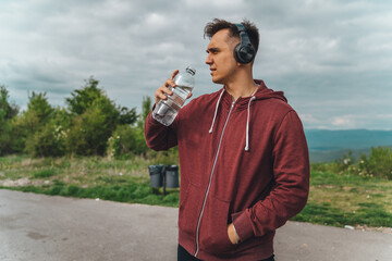 A man is listening to music while preparing for a long run outside during the day