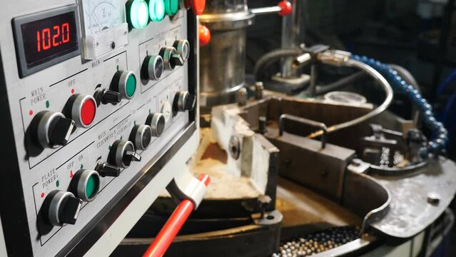 Bearing balls production in factory. Shot through remote control panel with buttons and toggle switches. manufacture of bearings. Grinding balls. Production of metal balls in plant, movement of hot