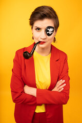 A woman with a pirate patch over one eye smokes a pipe. A sly expression on his face. Short...