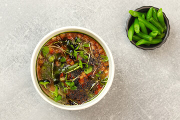 Vegetable soup minestrone in eco paper takeaway bowl on dark background. Healthy food delivery concept. Free space for text.