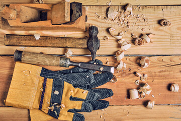 Carpenters tool kit, hammer, chisel and plane with gloves wooden background.