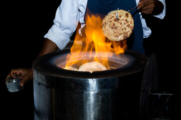 Chef make Naan bread in front of the tandoori oven
