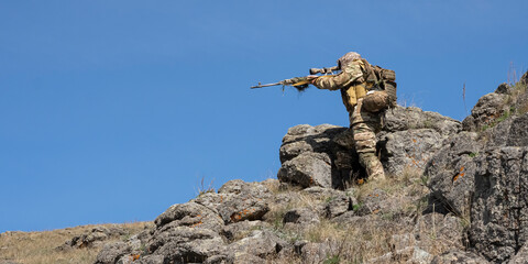 Ambush in the mountains - special forces professional sniper aiming at the enemy in the mountains.