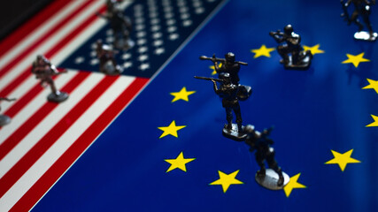 The concept of the economic and political crisis between the United States and the European Union, toy soldiers attacking each other against the background of national flags.