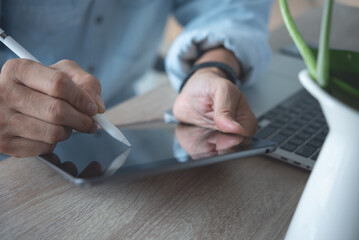 Close up of business man using electronic pen or stylus pencil signing e-document on digital...