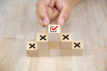 Hand choose check mark on cube wooden toy block stack with cross symbol for true or false changing...