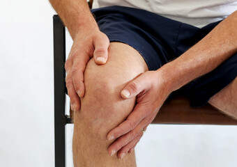 a man got injured holding on knee because of pain from overuse knee or workout.  Injury from...