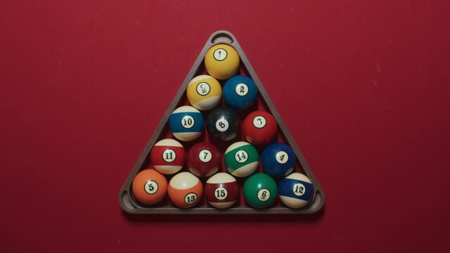 Top central still view on triangle form pyramid of 15 colorful pool balls on red felt bright background under direct light before beginning of weekend hobby game with friends, local sport competition