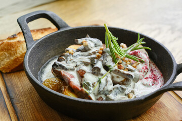 Frying pan with baked potatoes with mushrooms and steak with sauce. Shallow depth of field