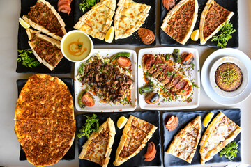 Traditional Turkish cuisine. Pizza, pita, pidesi, sucuk, hummus, kebab. Many dishes on the table. Serving dishes in restaurant. Background image. Top view, flat lay