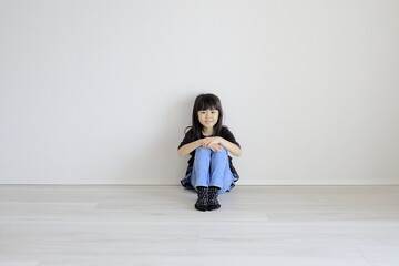 床に体育座りをする女子小学生 (7歳)