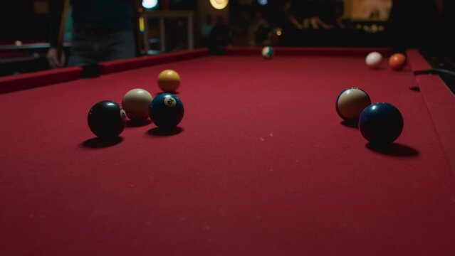 Unrecognized people, group of friends, players playing billiard, hitting colorful pool balls on red felt background table with cinematic dark light in local pub, bar, club on weekend, trip, vacation