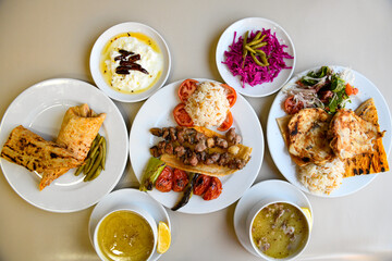 Delicious meat kebab with fresh vegetable salad served with variety of Turkish dishes and appetizers. Top view of assorted Turkish food and meze, tasty and healthy Mediterranean cuisine.