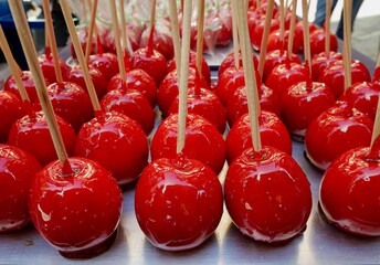 Sweet glazed red candy apples on wooden sticks for sale.