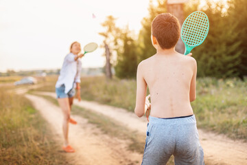 Mom and child boy playing badminton or beach tennis and have a good time and leisure outdoors at...