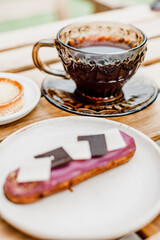 A mug of black tea and a sweet eclair cake on the table