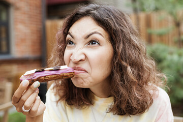 A girl sniffs a disgusting smell from a spoiled eclair cake