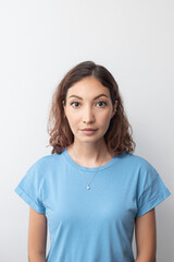 A Middle Eastern or Indian girl poses in casual clothes in a studio against a gray wall