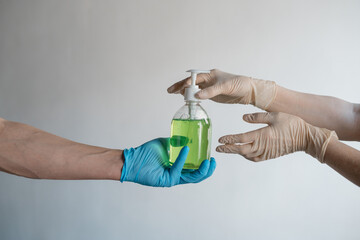 Naklejka premium Men's and women's hands give each other liquid soap on a white background. High quality photo
