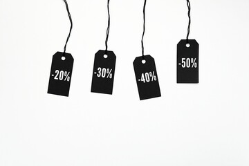 Black Friday sale, discounts, decrease in prices concept, four black price tags with percent sign hanging on black strings, white background.