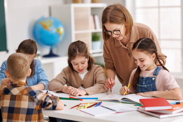 Fototapeta premium Teacher helping children with schoolwork