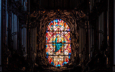 Virgin Mary in the stained glass window and an old musical organ