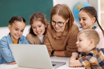 Fototapeta na wymiar Teacher and pupils using laptop