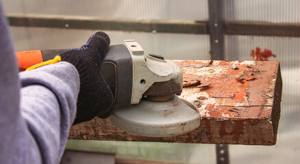 a man is grinding a board. Removing old paint from boards. Carpentry work.