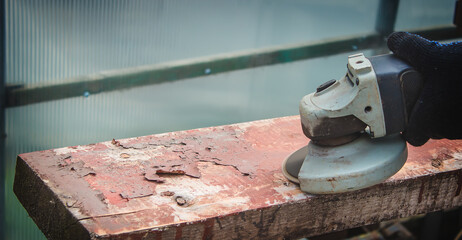 a man is grinding a board. Removing old paint from boards. Carpentry work.