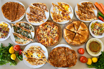 Traditional Turkish cuisine. Pizza, pita, pidesi, sucuk, hummus, kebab. Many dishes on the table. Serving dishes in restaurant. Background image. Top view, flat lay