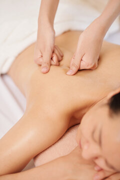 Hands massaging upper back of young female client