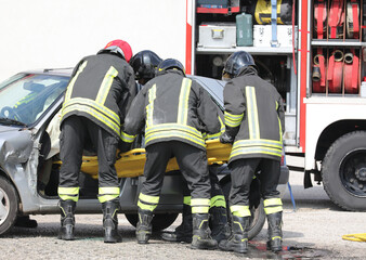 Fototapeta premium firefighters pulling the from the bumpy car after the traffic accident on the highway