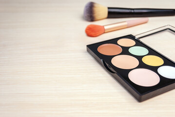 A palette for contouring the face, makeup brushes on a beige background. Professional makeup. Copy space