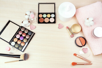 Top view of a women's table with makeup, including lipstick, eye palette, contouring palette, creams, brushes and others. Flat lay.