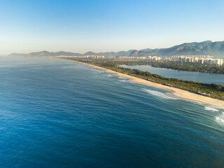 Aerial view of Reserva beach, Marapendi lagoon and car traffic on Lucio Costa avenue. Barra da Tijuca and Recreio, in Rio de Janeiro, Brazil. Sunrise. Sunny day. Drone photo. Praia da Reserva