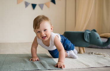 Caucasian baby boy crawls on the floor in the children's room with toys. Baby learns to crawl