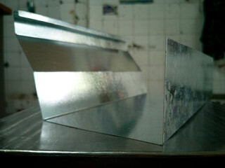 Galvanized steel gutters is put on the stainless table, short Galvanized gutters with blurred background, photo is Depth of Field style