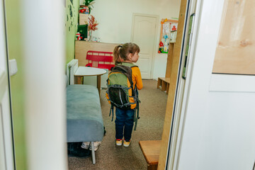 Back view of little girl with backpack going to school