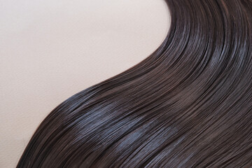 texture of beautiful glossy long hair.Curl female healthy hair. Concept hairdresser spa salon. strand of brunette silky hair.