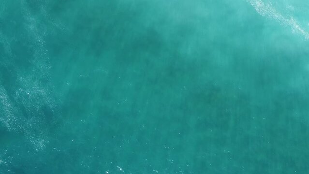 top down view shot of stunning blue mediterranean sea with turquoise waves. Drone flight over the ocean on a sunny day. Deserted beach with one person, peaceful calm sea background, aerial view, drone
