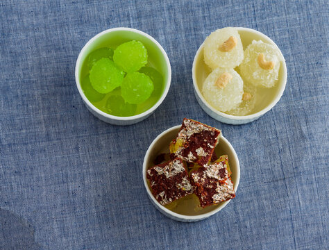 Three bowls containing assorted petha, which is an Indian dessert from Agra,India.Petha comes in many  flavors like chocolate petha,pan petha,angoori petha and coconut petha. Top view.