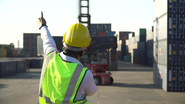 asian  Foreman talking on walkie-talkie control forklift loading Containers box at warehouse logistic in Cargo freight ship for import export . worker shipping at high construction site