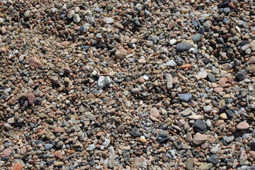 A closeup image of the ground of the beach full of pebbles in a small town in the Mediterranean Sea. Vacations, summer, holidays.