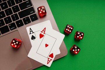 Playing cards with aces and red dice on a laptop. Top view. Casino concept