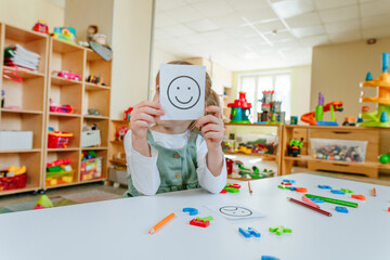 Little girl showing card with positive happy emotion