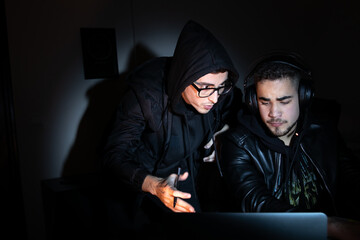 Portrait of focused hackers at work. Men in casual clothes looking at laptop screen, typing, talking. Hacking, computer concept